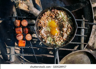 Camp Cooking, Grains And Sausage Cooking Over The Fire