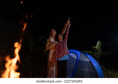 Camp family concept, children and mom pointing star on dark sky,  mother and daughter smile joyful on fire camp and looking sky on night background, happy for outdoor acitvity of family lifestyle time - Shutterstock ID 2217196395