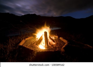 Camp Fire Beside Lake And Mountains.