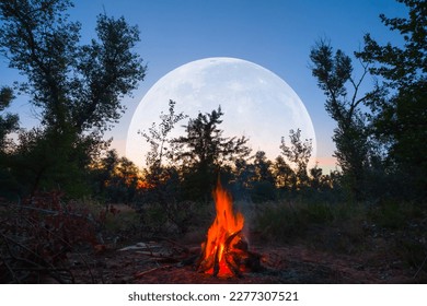 camp fire on forest glade with huge moon rising above, twilight outdoor camping scene - Powered by Shutterstock