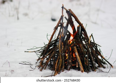 Camp fire in winter time, surrounded by snow.