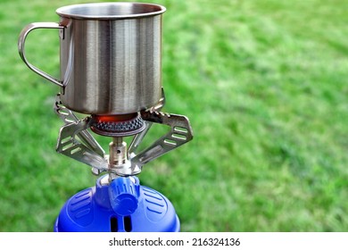 Camp Gas  Cooker And Steel Tea Mug. Background With Copy Space