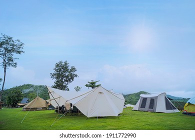 Camp and pitch a tent under the forest on the hill with a beautiful morning sun. Canvas cotton Bell tent in the yard decorated for summer kids party