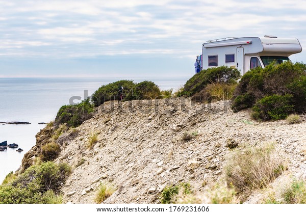 Camper car camping\
on cliff above Cala Mochuela, spanish landscape along Almeria\
coast. Traveling in\
motorhome.
