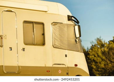 Camper car with external thermal screen blind at front windscreen. Camping on nature. Holidays and travel in motor home.
