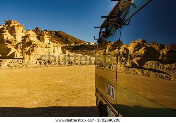 Camper car on parking area at eroded yellow\
sandstone formations, Enchanted City of Bolnuevo, Murcia Spain.\
Tourist attraction.