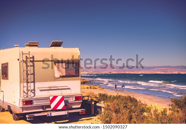 Camper car
recreation vehicle with ladder, broken window and rear warning
striped sign for safety camping on sea
shore