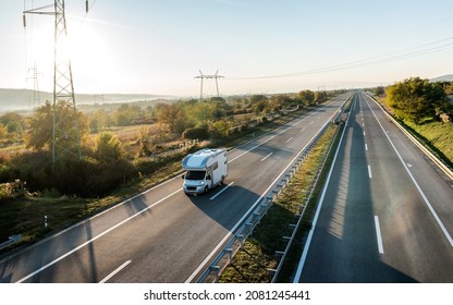 Camper Car Recreational Vehicle With Alcove Driving Along The Rural Countryside Highway. Holidays And Travel In Motor Home.