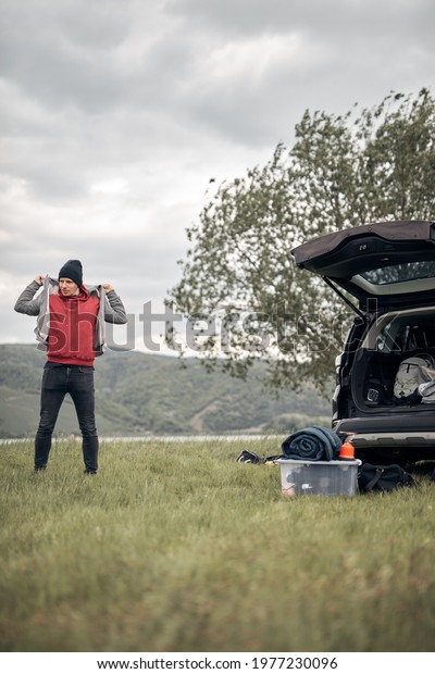 Camper packing and unpacking from a car\'s back\
door in nature.