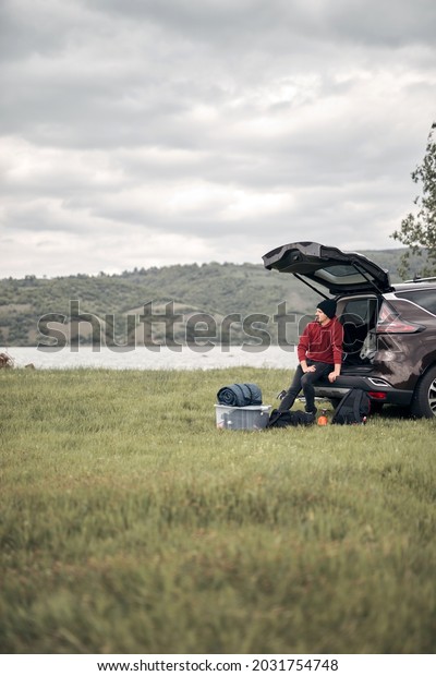 Camper packing and unpacking from a car\'s back\
door in nature.