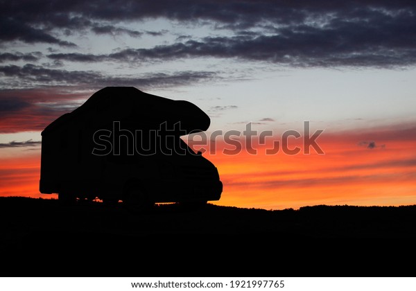 Camper recreational vehicles\
at sunset. Camping in nature. Holidays and travel in camper van\
home.