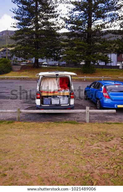 Camper van geared\
for van life on the road with bed, boxes and privacy curtain. Car\
living on an adventure road trip in Australia. Lived in mini van\
parked on a beach car\
park.