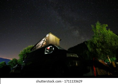 Camper Van With Glowing Tent On Top Under A Star Spangled Sky With The Milky Way In The Background