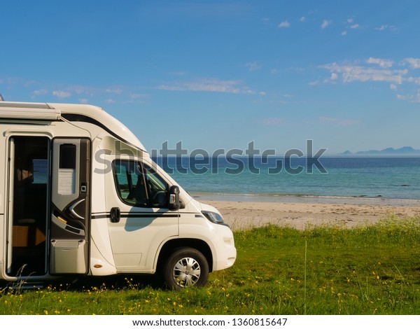 Camper van motor home on sea coast Gimsoysand\
beach in summer. Camping on ocean shore. Lofoten archipelago\
Norway. Vacation and travel in\
caravan.