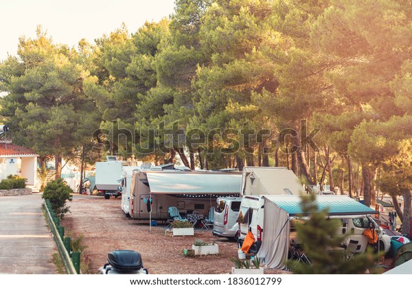 Campervan caravan vehicle for van life holiday\
on mobile home camper mobile motor home. Golden sunshine sneaking\
through sparse trees of camping. Roof of campervan is covered in\
colourful sunshine