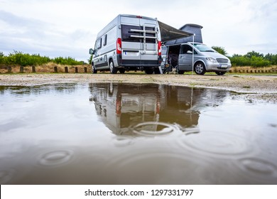 Campervan Or Motorhome Camping On Rainy Day With Rain Puddles. Family Vacation Road Trip With Camper Van, Motor Home Or RV In With Bad Weather. Holiday Travelling To Atlantic Ocean - Spain Or Portugal