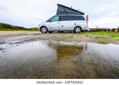 Campervan Or Motorhome Camping On Rainy Day With Rain Puddles. Family Vacation Road Trip With Camper Van, Motor Home Or RV In With Bad Weather. Holiday Travelling To Atlantic Ocean - Spain Or Portugal