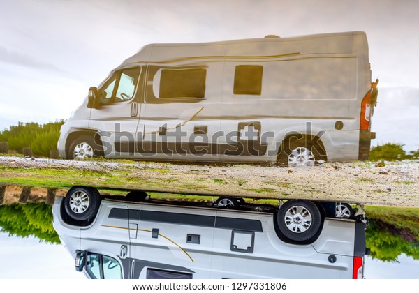 Campervan or motorhome camping on rainy day with\
rain puddles. Family vacation road trip with camper van, motor home\
or RV in with bad weather. Holiday travelling to Atlantic ocean -\
Spain or Portugal