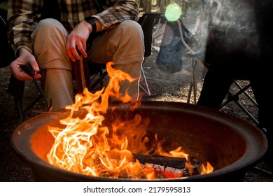 Campfire burning in a firepit . People sitting around. Camping life. Outdoor family recreation. - Powered by Shutterstock