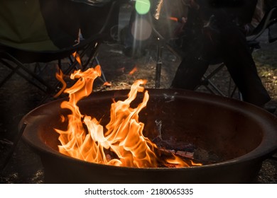 Campfire Burning In A Firepit . People Sitting Around. Camping Life. Outdoor Family Recreation.