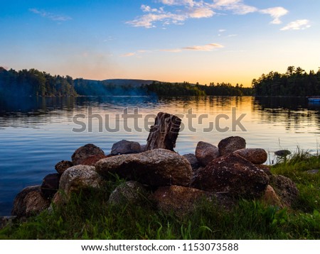 A campfire burning in a stone fire ring along the shore of a river in Maine.