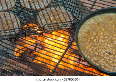 Campfire cooking baked beans in a skillet and seasoned hamburgers - Powered by Shutterstock