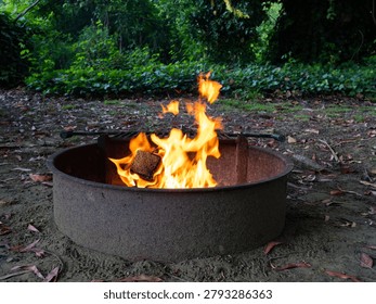 Campfire flames dance inside a rustic metal fire pit