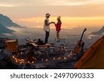 Campfire in the midst of nature. There is an Asian couple making coffee and playing music together while setting up a tent on a mountaintop with a view of nature in Chiang mai, Thailand