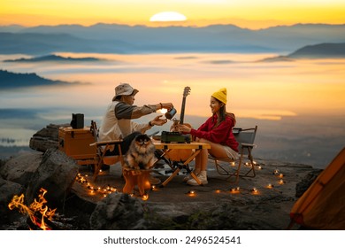 Campfire in the midst of nature. There is an Asian couple making coffee and playing music together while setting up a tent on a mountaintop with a view of nature in Chiang mai, Thailand  - Powered by Shutterstock