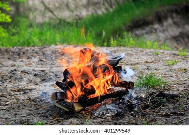 Campfire On Meadow In Green Forest At Sunny Spring Day