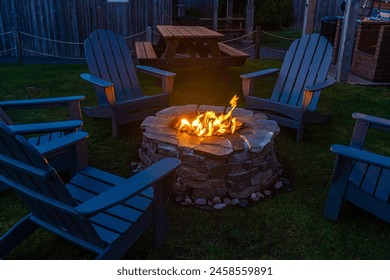 Campfire pit blazing fire surrounded by  adirondack chairs at night. - Powered by Shutterstock