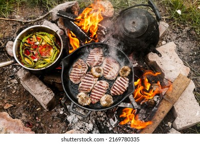 Campfire red meat in pan, near the fire outdoors. bushcraft, adventure, tea, knife and camping concept - Powered by Shutterstock