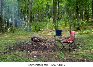 Campfire Scene With Two Folding Chairs Set Up Around A Fire Ring In The Woods