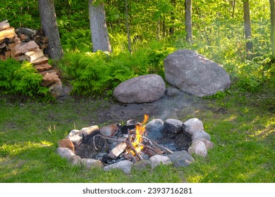 Campfire in stone fire ring, pit, cut camp wood, with large boulders as background in the Chippewa National Forest, northern Minnesota USA