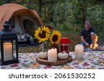 Campground picnic table decorated for fall with tent and campfire in blurred background