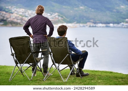 Camping, chair and people relax at lake with landscape in countryside, nature or calm vacation. Summer, holiday and back of friends sitting on grass at river with peace in environment together