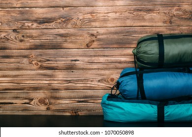 Camping Equipment, Sleeping Bags, Tent S On Wooden Background With Copy Space For Text