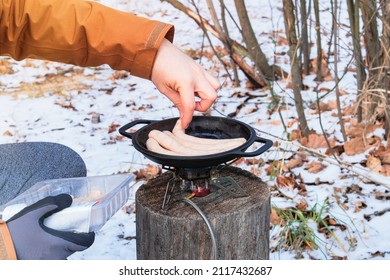 Camping food making. Tourist foods in outdoor activities. Sausages in bowler in the forest in winter.