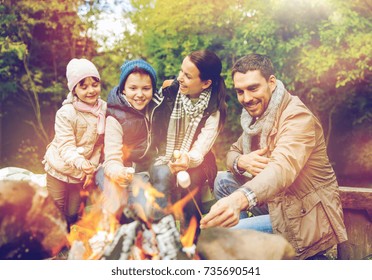 Camping, Hike And People Concept - Happy Family Roasting Marshmallow Over Campfire