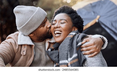 Camping, laugh and couple in nature kiss on holiday, vacation and adventure on weekend together. Relax, dating and black man and woman outdoors for bonding, loving relationship and sitting by tent - Powered by Shutterstock