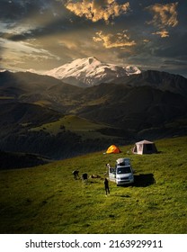 Camping In The Mountains With Tent Standing On A Hill, Night And Sunset Landscape With Helipad For Drone