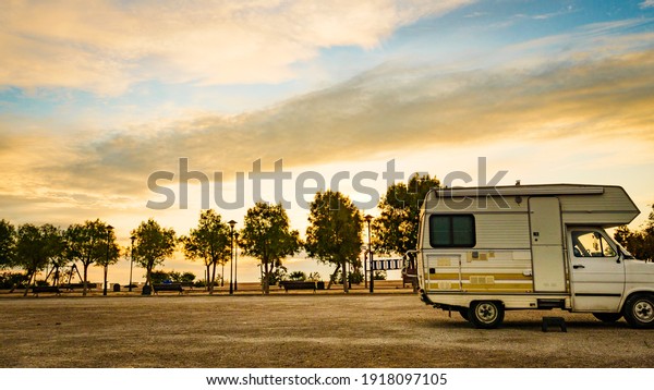 Camping on sea shore. Old camper car with alcove\
on beach at evening.
