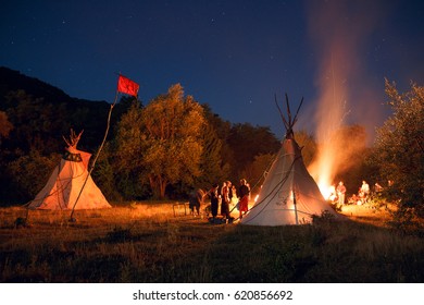 Camping with people in night forest with tipi and big bonfire on dark forest background. Horizontal outside shot. - Powered by Shutterstock