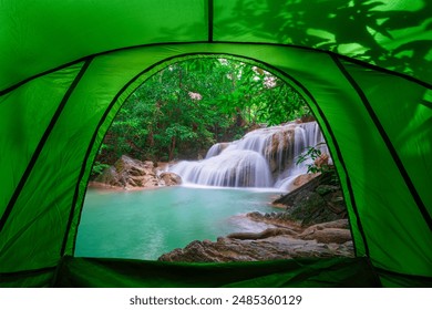 camping tent, looking inside the tent to view the emerald blue water in Erawan National Park. Erawan Waterfall is a beautiful natural rock waterfall in Kanchanaburi, Thailand.