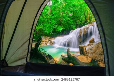 Camping tent, looking inside the tent to view the emerald blue water in Erawan National Park. Erawan Waterfall is a beautiful natural rock waterfall in Kanchanaburi, Thailand.  