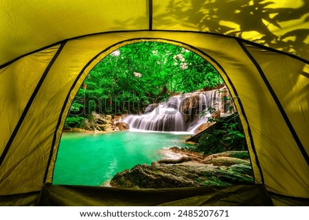 camping tent, looking inside the tent to view the emerald blue water in Erawan National Park. Erawan Waterfall is a beautiful natural rock waterfall in Kanchanaburi, Thailand.