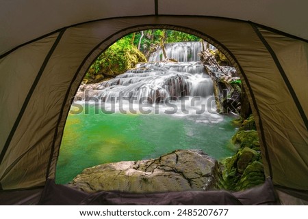 camping tent, looking inside the tent to view the emerald blue water in Erawan National Park. Erawan Waterfall is a beautiful natural rock waterfall in Kanchanaburi, Thailand.