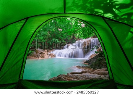 camping tent, looking inside the tent to view the emerald blue water in Erawan National Park. Erawan Waterfall is a beautiful natural rock waterfall in Kanchanaburi, Thailand.