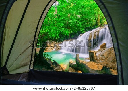 Camping tent, looking inside the tent to view the emerald blue water in Erawan National Park. Erawan Waterfall is a beautiful natural rock waterfall in Kanchanaburi, Thailand.  