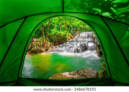 camping tent, looking from inside the tent to view the emerald blue water in Erawan National Park. Erawan Waterfall is a beautiful natural rock waterfall in Kanchanaburi, Thailand.